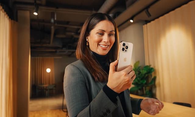 Smilende forretningskvinne som bruker iPhone 16 Pro