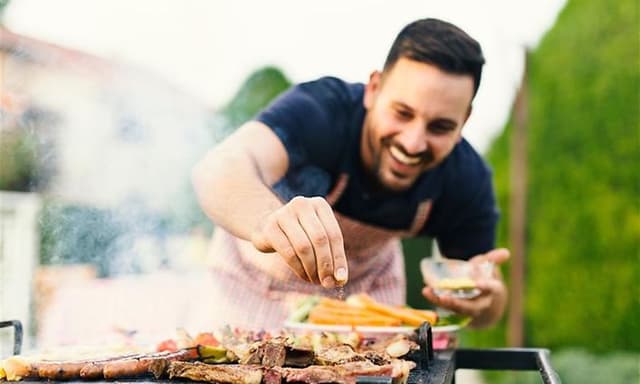 Mann i hagemiljø nyter grilling utendørs