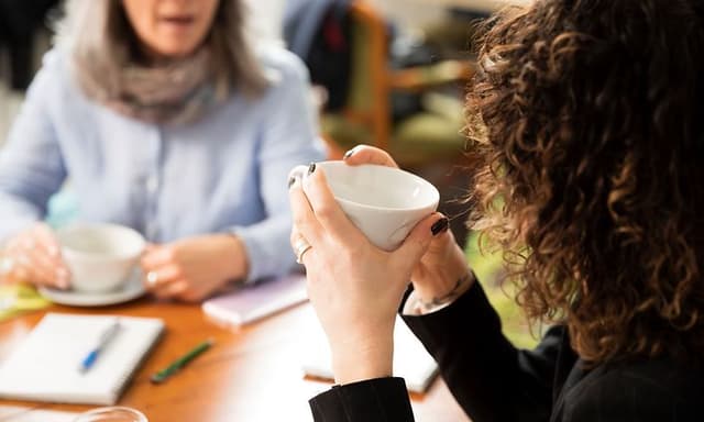 B2B - To kvinner med kopper ved bord