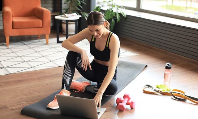 Hjemmetræning: En kvinde sidder på yogamåtte derhjemme