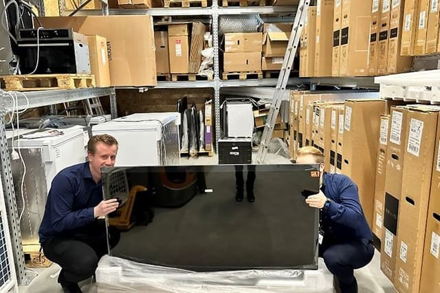 Udpakning af TV: To medarbejdere pakker et TV korrekt ud på lager i Elgiganten
