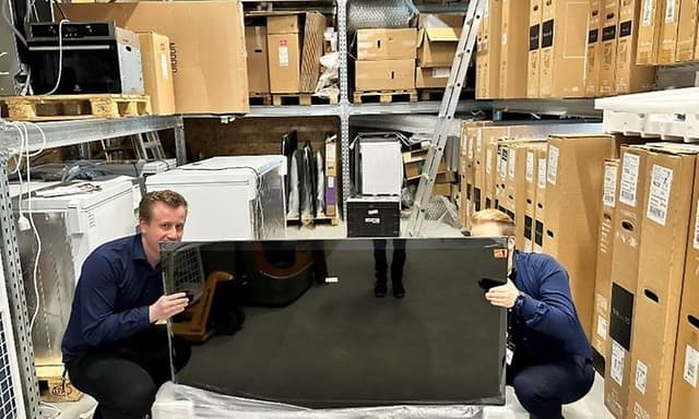 Udpakning af TV: To medarbejdere pakker et TV korrekt ud på lager i Elgiganten