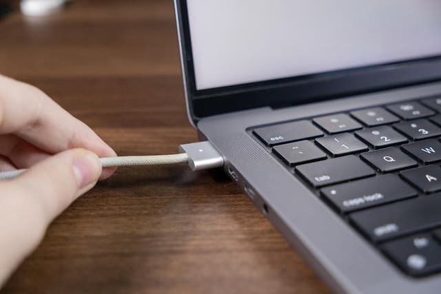MagSafe charging cable being connected to a MacBook