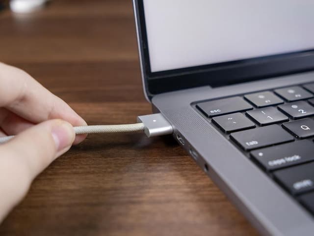 MagSafe charging cable being connected to a MacBook