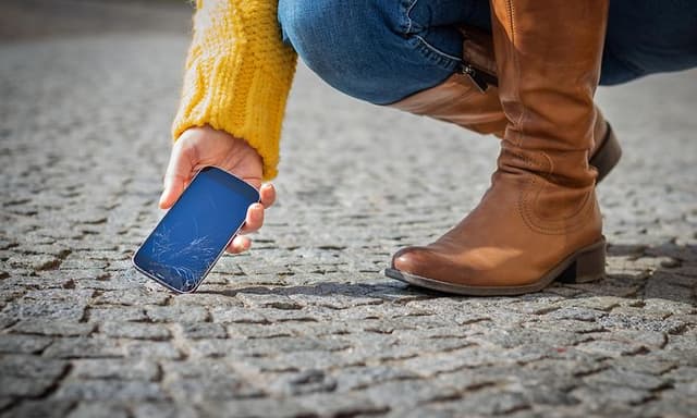 Woman picking up broken smartphone from street