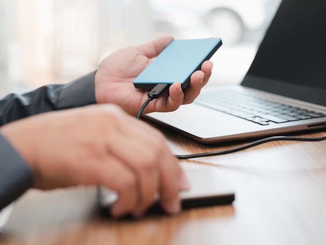 En man kopplar in en extern hårddisk i en laptop