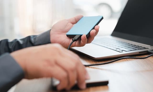 En man kopplar in en extern hårddisk i en laptop
