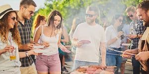 Joukko ystäviä on kerääntynyt grillaamaan ulkona aurinkoisessa säässä