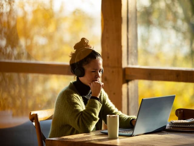 Kvinne sitter ved bordet og jobber med sin bæarbar PC