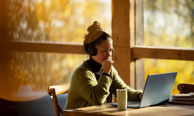 Kvinne sitter ved bordet og jobber med sin bæarbar PC