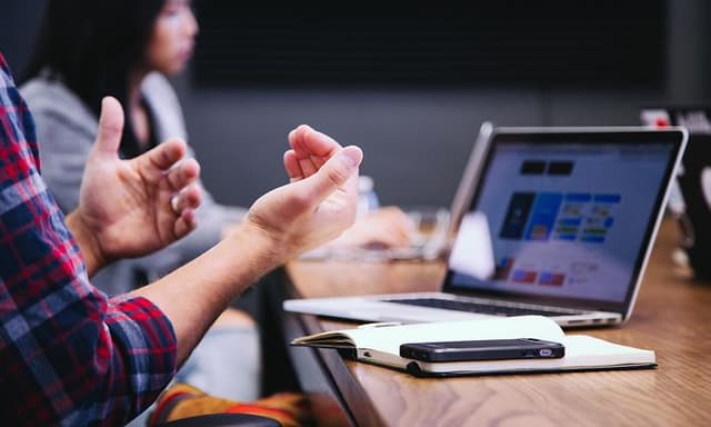B2B - AI-PC - Kokouksen osallistuja istuu palaveripöydän ääressä tietokoneen kanssa