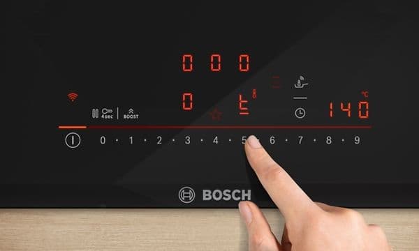 Henkilö säätää Bosch-lieden lämpötilaa 