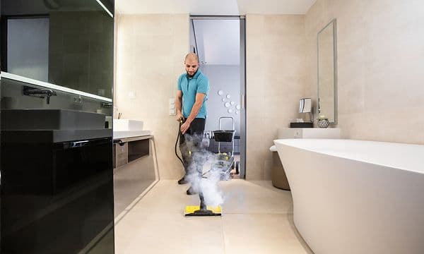 A black and yellow steam cleaner with a hose and nozzle attachment on a white background.