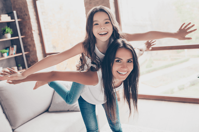 Inomhusklimat med en tjej och en mamma som låtsas flyga tillsammans i vardagsrummet.