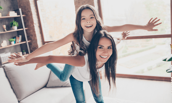 Indoor Climate hero banner with a girl and a mother pretending to fly together in the living room