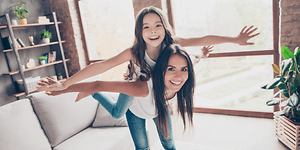 Indoor Climate hero banner with a girl and a mother pretending to fly together in the living room