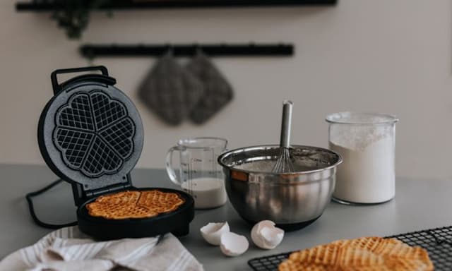 Vaffeljern på en kjøkkenbenk sammen med ingrediensene til vaffelrøre