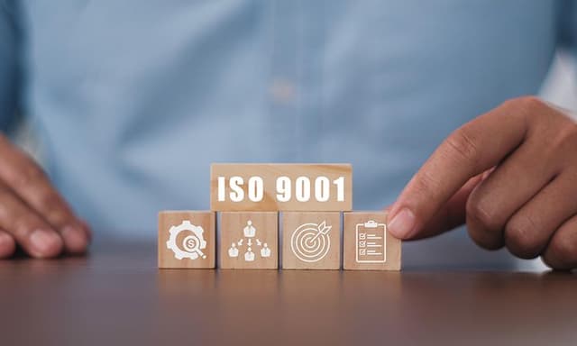 Træklodser på et bord, hvor der står ISO 9001 på en af dem