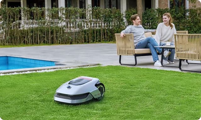 Couple in a garden with a grey Robotic lawn mover on the lawn