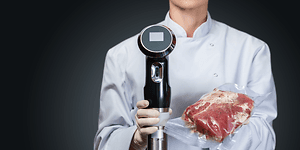 Sous Vide - A chef holding a vacuum meat and sous vide circulator in her hands