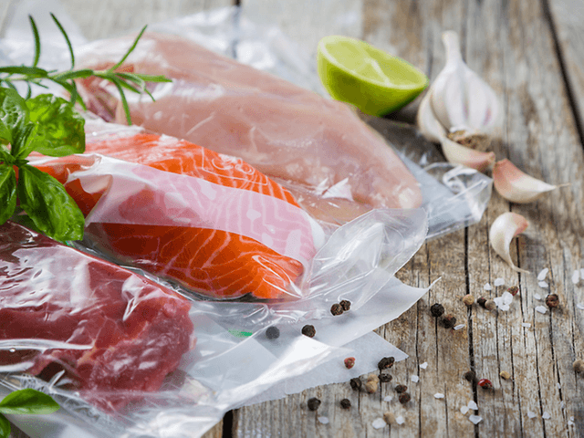 Perfect Results with Sous Vide Cooking - vacuum packed fish and chicken next to herbs, garlic and lime