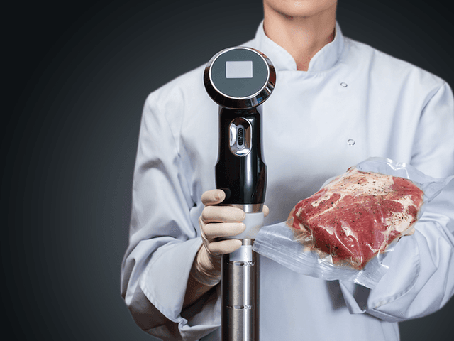 Sous Vide - A chef holding a vacuum meat and sous vide circulator in her hands