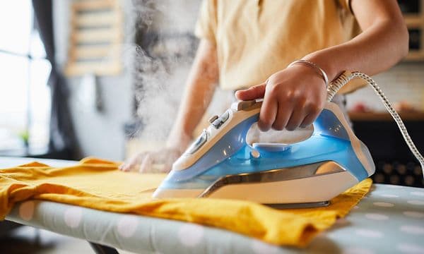 Bedste dampstrygejern: Strygejern anvendes af person på krøllet tøj