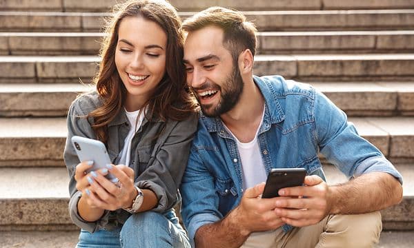 Man and woman smiling and looking at phones