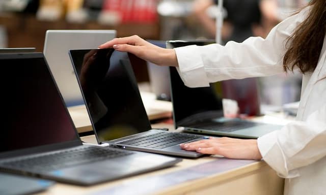 Billig laptop: Kvinde i butik ser efter en billig bærbar PC