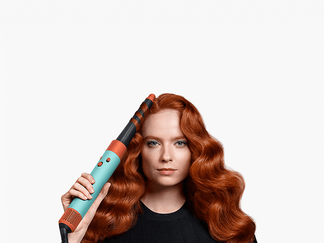 Dame med rødt hår bruker Dyson Airwrap™ multi-styler og dryer for hårstyling - i.d. curl™ technology