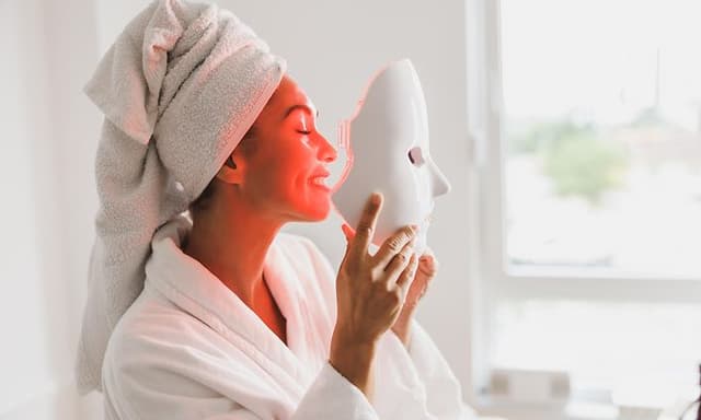 Dame som får behandling fra LED-maske hjemme