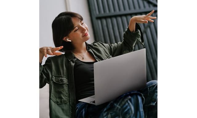 Sennheiser ACCENTUM Open earbuds in the ears of a woman sitting with her laptop