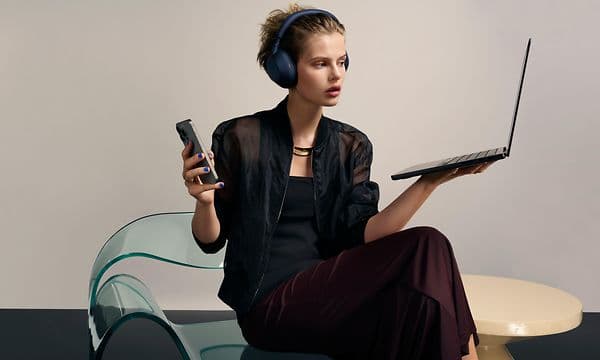 Sony WH-1000x m6 -Woman with headphones holding laptop