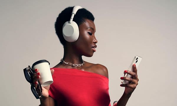 Sony WH-1000x m6 -kuulokkeet päässä oleva nainen katsoo puhelintaan