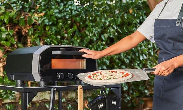 Mies paistaa pizzaa Ooni-pizzauunilla
