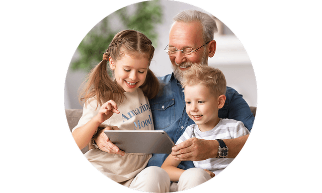 Tablet i hånden på mand, der sidder i sofa med to børn