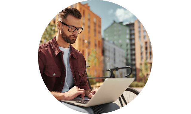 Laptop i skødet på mand, der arbejder udenfor