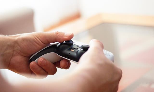 Mann som holder PlayStation 5 -kontroller i hendene