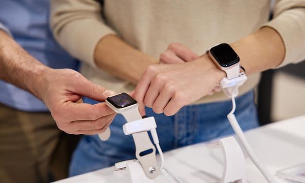 A man and a woman in a store looking at smartwatches