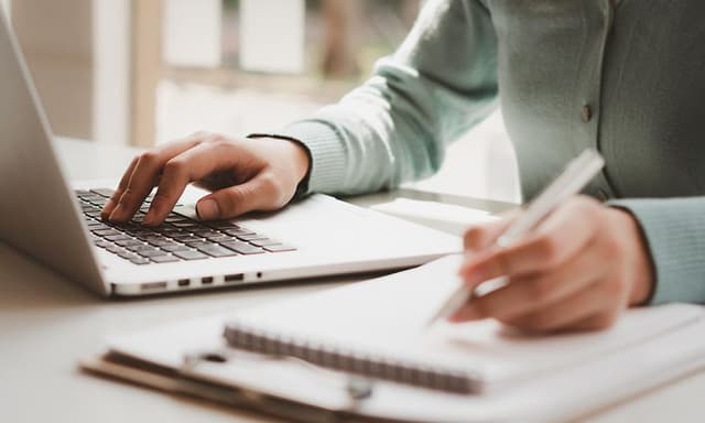 B2B - Woman work on laptop and taking notes on a notepad