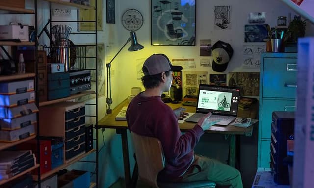 Computing - AI PC - Young man sitting by his desk using a laptop