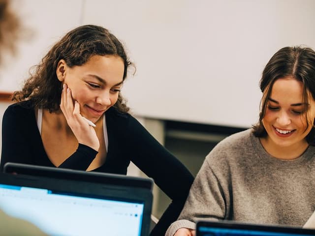 Unge kvinder med AI-PC'er i studiemiljø