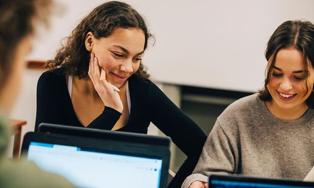 Unge kvinder med AI-PC'er i studiemiljø