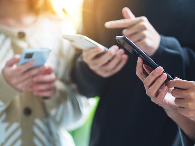Group of young people using and looking at mobile phone together