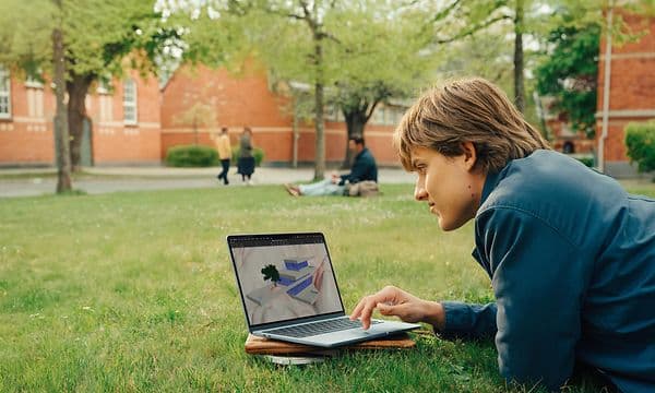 Opiskelija MacBook Airin kanssa puistossa