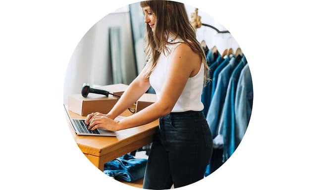 Woman typing on a laptop in clothing store