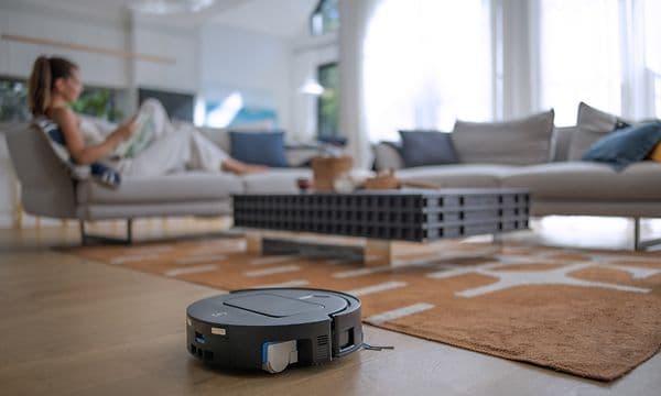 Ecovacs Deebot T80 OMNI städar medan kvinnan kopplar av i en soffa