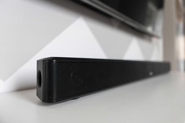 Musta soundbar-kaiutin valkoisella tv-tasolla