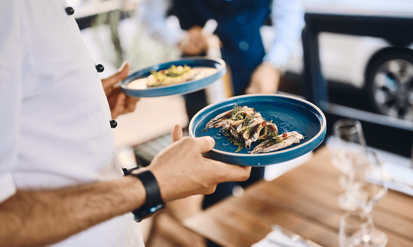 Tjener bærer to tallerkener mad til et bord i en restaurant