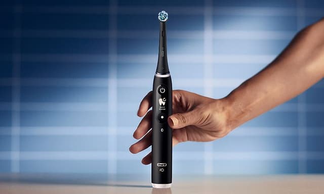 Person holder en Oral-B iO6 elektrisk tandbørste i sort